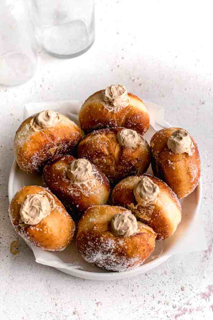 Coffee Espresso cream filled bombolinis aka fried Italian doughnuts in a white plate