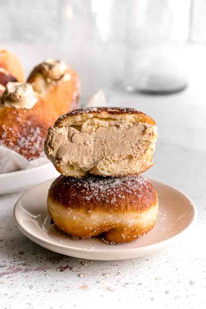 Coffee Espresso cream filled bombolinis aka fried Italian doughnuts in a white plate cut in half