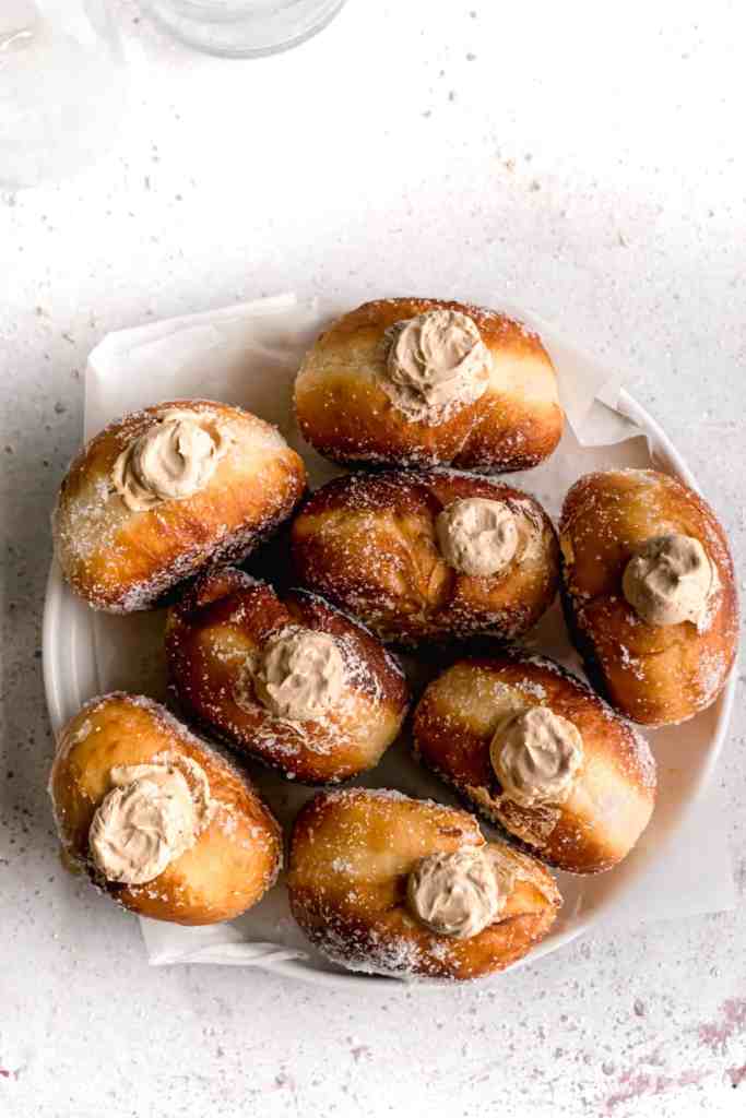 Coffee Espresso cream filled bombolinis aka fried Italian doughnuts in a white plate