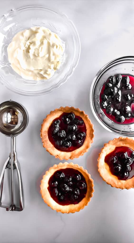 Blueberry preserves poured into baked tart shells