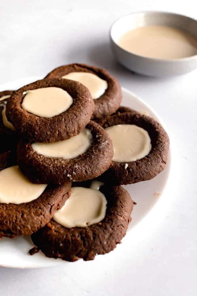 Chocolate tahini thumbprints stacked on a white plate