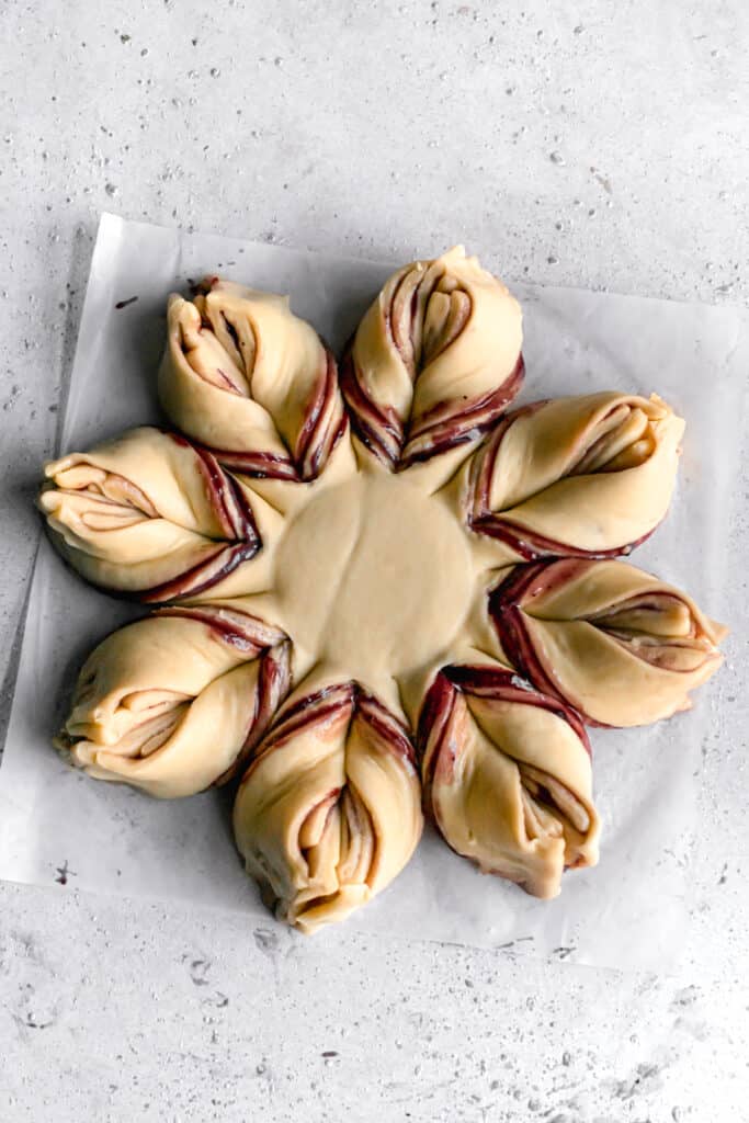 yeast dough for star bread on a parchment paper rolled out into a circle and shaped like a star