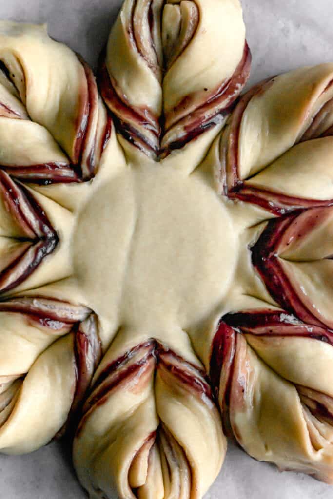 yeast dough for star bread on a parchment paper rolled out into a circle and shaped like a star