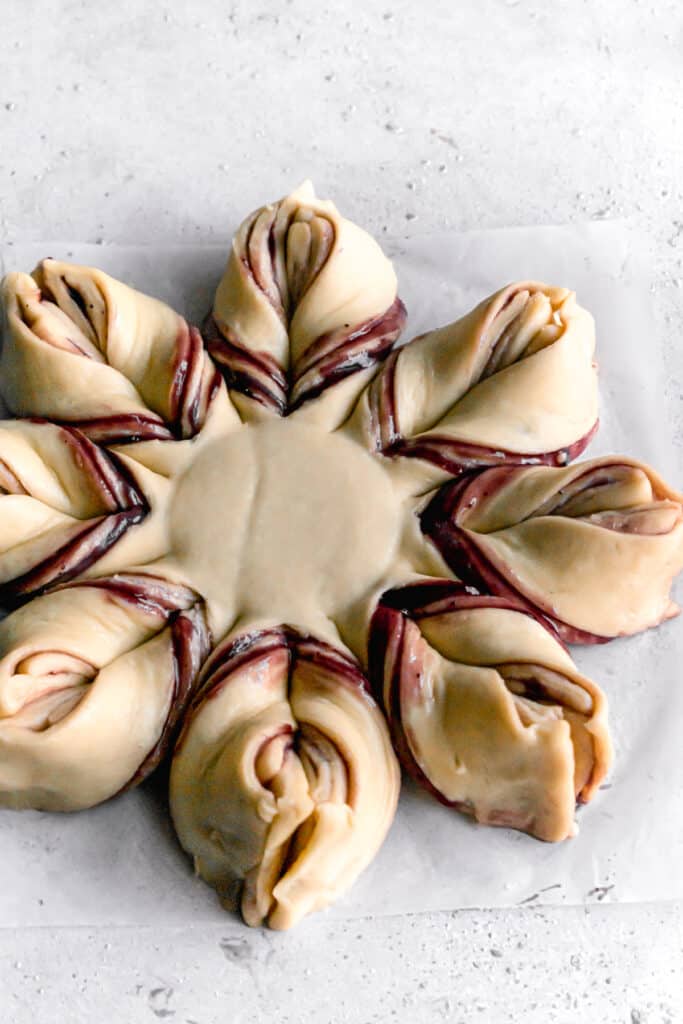 yeast dough for star bread on a parchment paper rolled out into a circle and shaped like a star