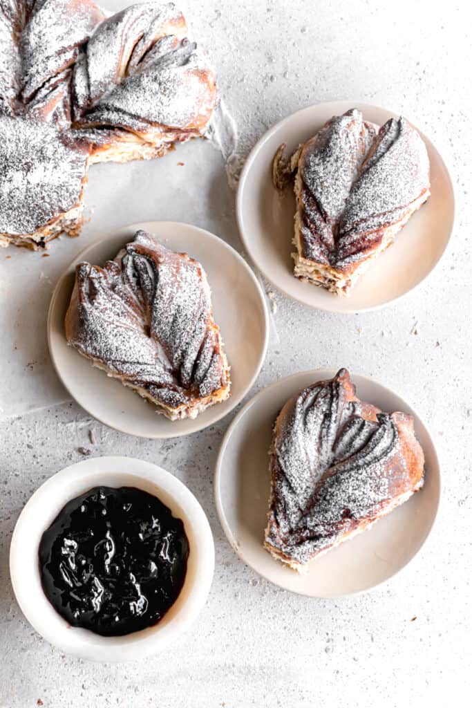 Baked and cut Blueberry jam cream cheese star bread slices on plates dusted with powdered sugar