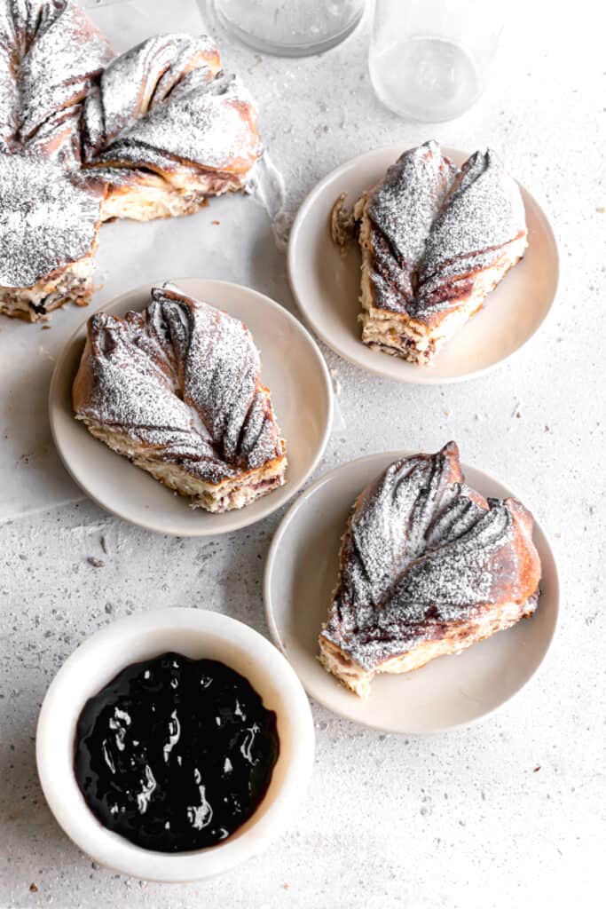 Baked Blueberry jam cream cheese star bread slices on plates dusted with powdered sugar