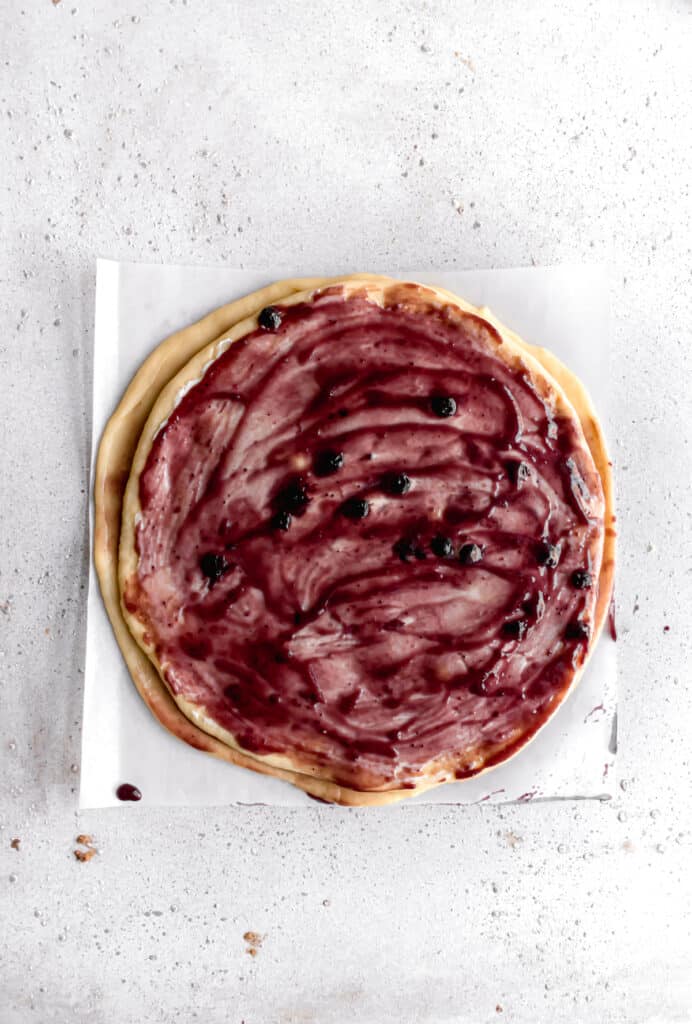 yeast dough for star bread on a parchment paper rolled out into a circle and layered with blueberry jam