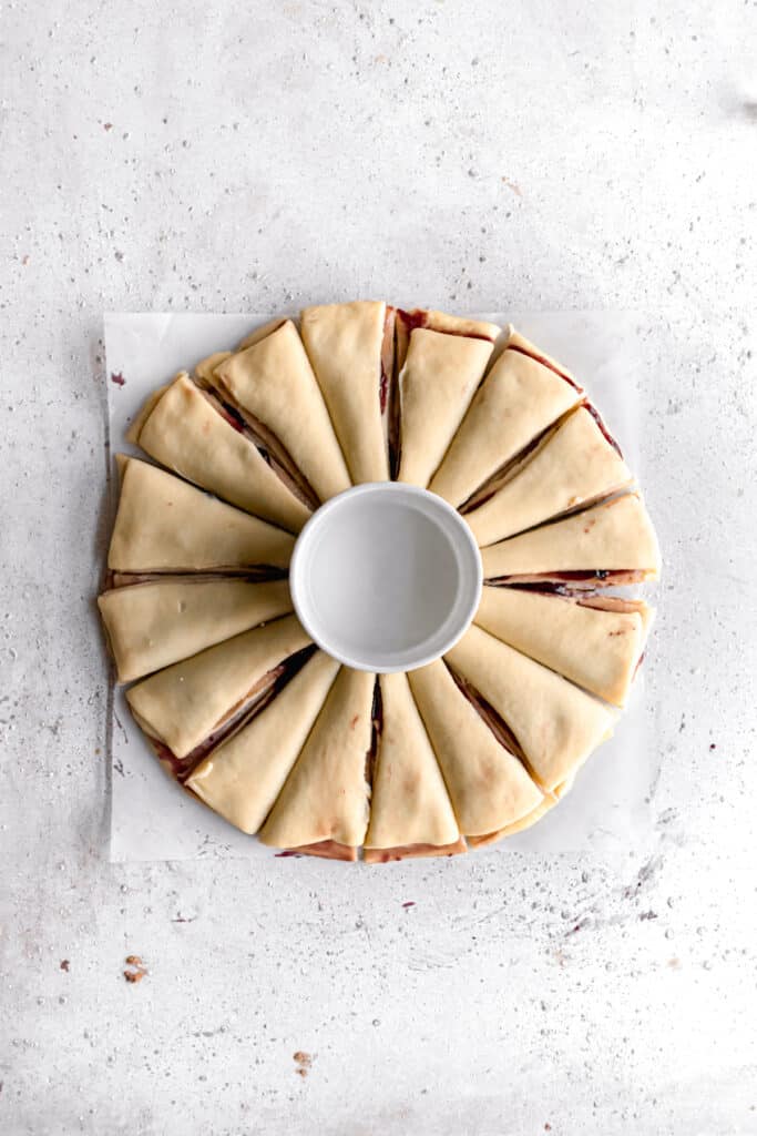 yeast dough for star bread on a parchment paper rolled out into a circle and cut into 16 parts