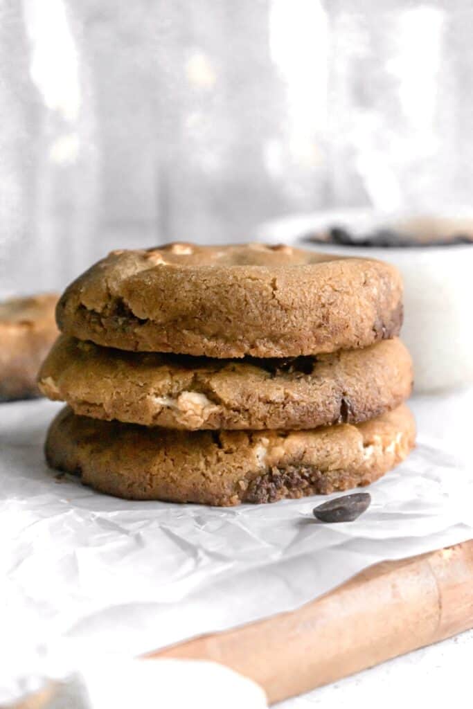 Large chocolate chip marshmallow cookies stacked on a parchment paper