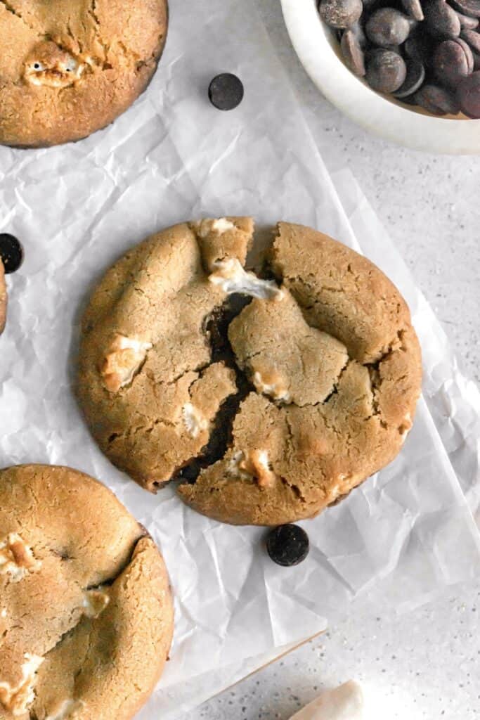 Large chocolate chip marshmallow cookie on a parchment paper with marshmallow pull