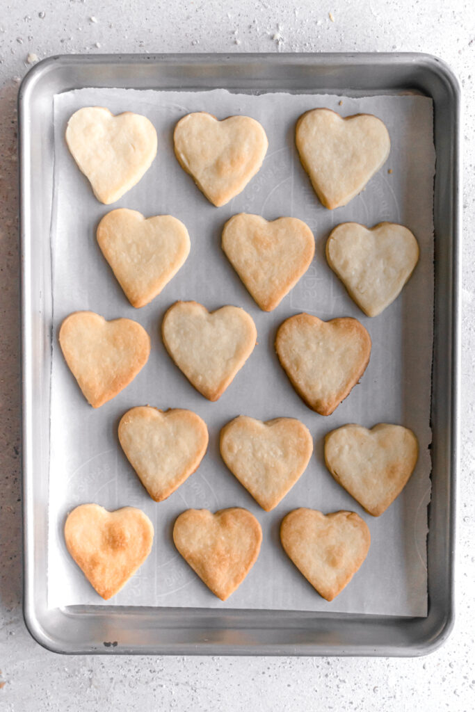 baked heart shaped shortbread cookies in a parchment paper in a baking pan